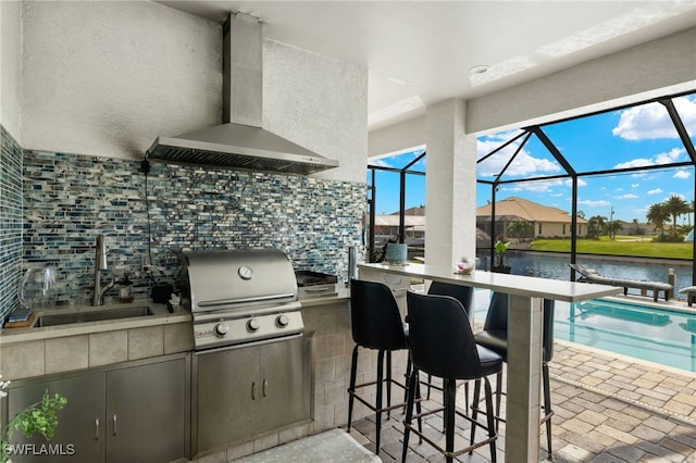 view of patio featuring area for grilling, a grill, sink, glass enclosure, and a water view