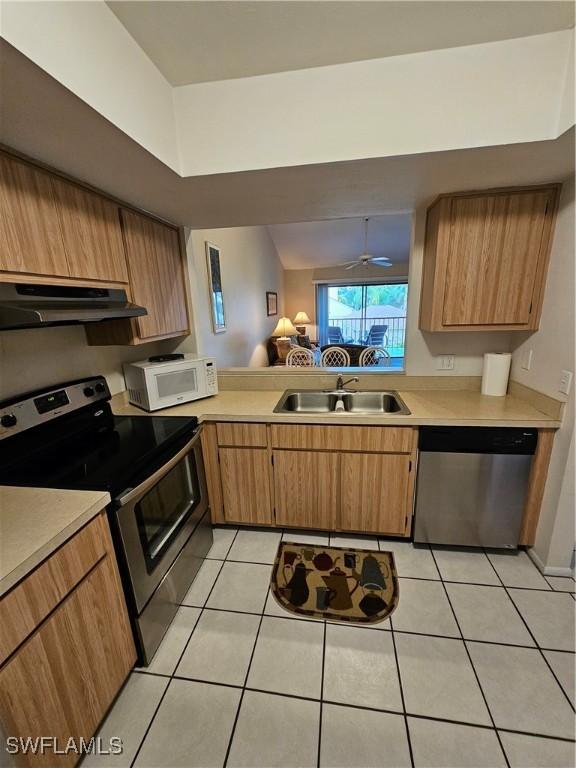 kitchen featuring under cabinet range hood, stainless steel appliances, light countertops, and a sink