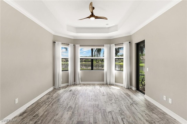 unfurnished room featuring a raised ceiling, ceiling fan, light hardwood / wood-style flooring, and ornamental molding