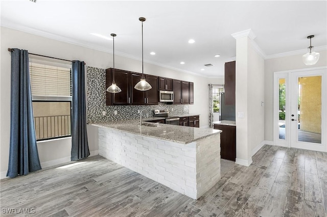 kitchen with pendant lighting, sink, appliances with stainless steel finishes, tasteful backsplash, and kitchen peninsula