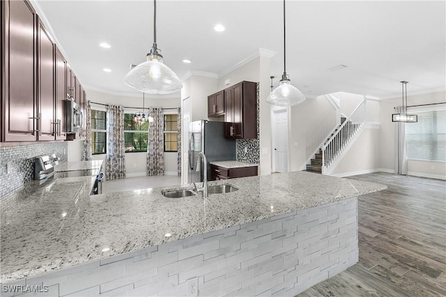 kitchen featuring stainless steel appliances, kitchen peninsula, sink, and pendant lighting