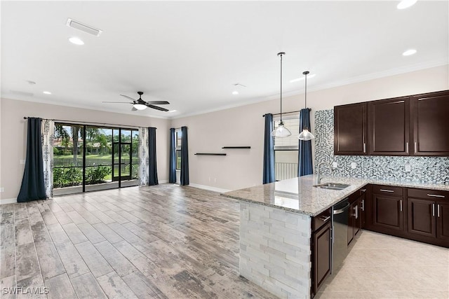 kitchen with sink, hanging light fixtures, ceiling fan, light stone countertops, and kitchen peninsula