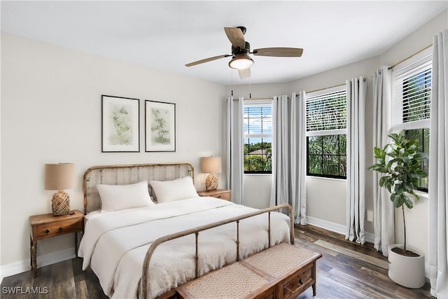 bedroom featuring ceiling fan, dark hardwood / wood-style floors, and multiple windows