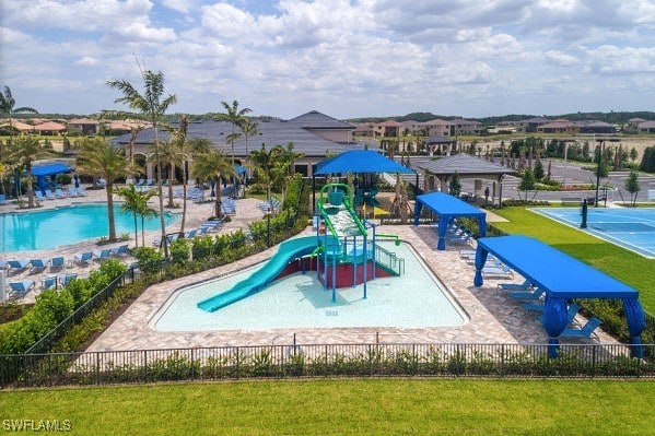 view of jungle gym featuring a lawn and tennis court