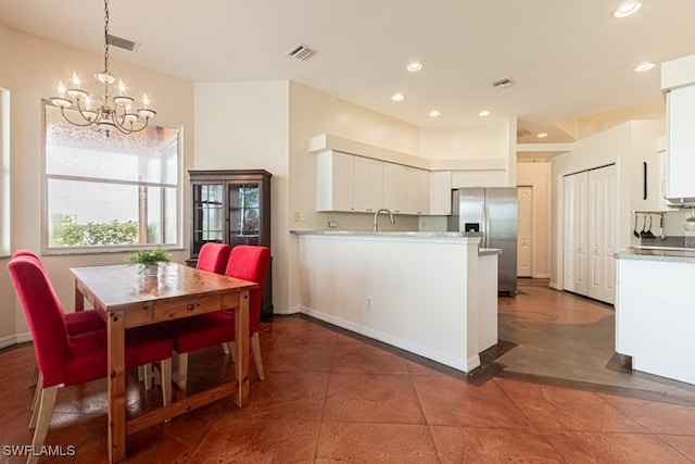 kitchen featuring hanging light fixtures, stainless steel refrigerator with ice dispenser, white cabinetry, and a chandelier