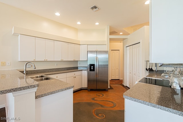 kitchen featuring sink, kitchen peninsula, white cabinetry, stainless steel refrigerator with ice dispenser, and black range oven