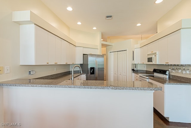 kitchen featuring white cabinets, white appliances, and kitchen peninsula