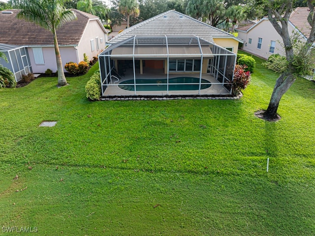 rear view of house with a lanai, a patio area, and a lawn