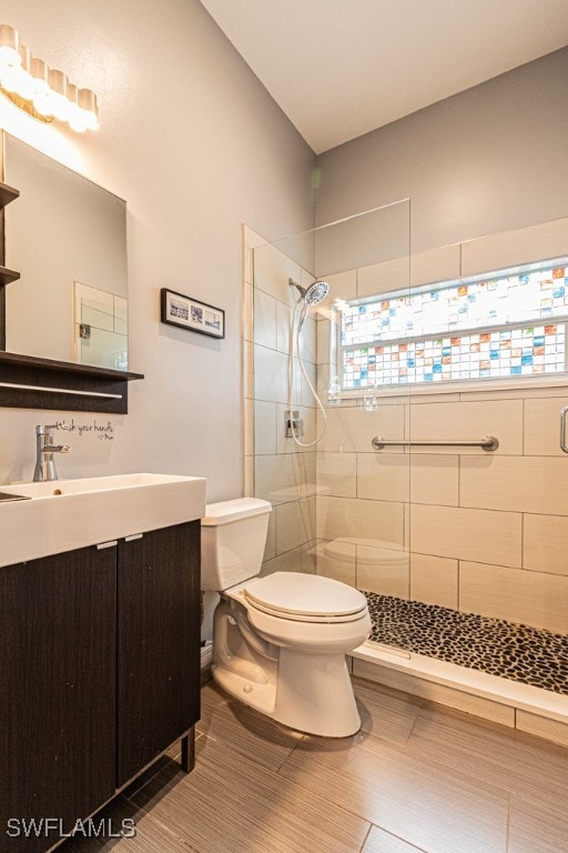 bathroom with vanity, toilet, and tiled shower