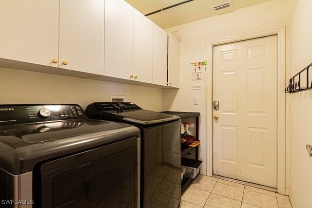 laundry area with separate washer and dryer, cabinets, and light tile patterned floors