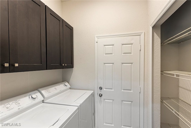 clothes washing area featuring washer and clothes dryer and cabinets