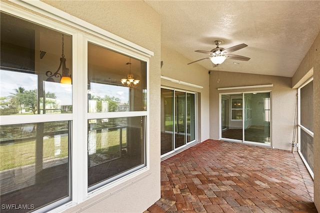 unfurnished sunroom with ceiling fan with notable chandelier and vaulted ceiling