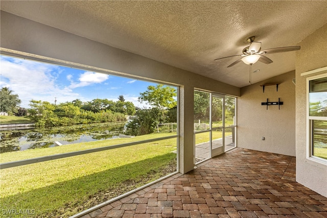 unfurnished sunroom featuring ceiling fan and a water view