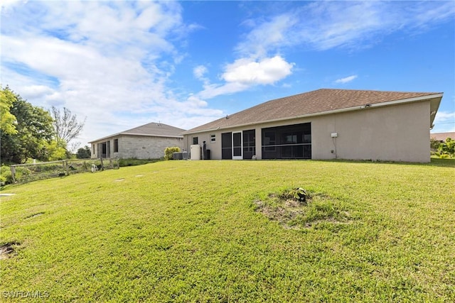 rear view of property with a yard, central AC, and a sunroom