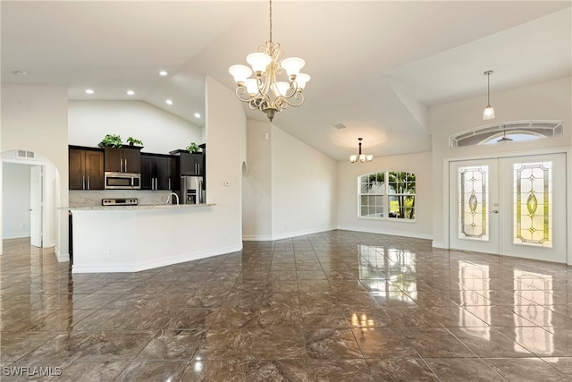 living room with a notable chandelier, sink, a high ceiling, and french doors