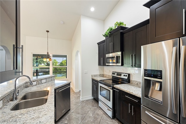 kitchen with sink, decorative light fixtures, light stone counters, stainless steel appliances, and a chandelier