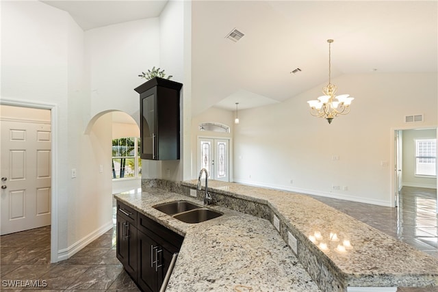 kitchen featuring light stone counters, sink, high vaulted ceiling, a notable chandelier, and a kitchen island