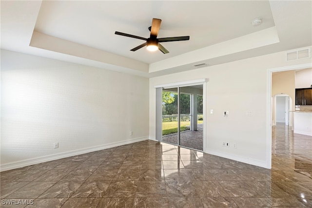 spare room featuring ceiling fan and a raised ceiling