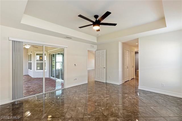 empty room featuring a raised ceiling and ceiling fan