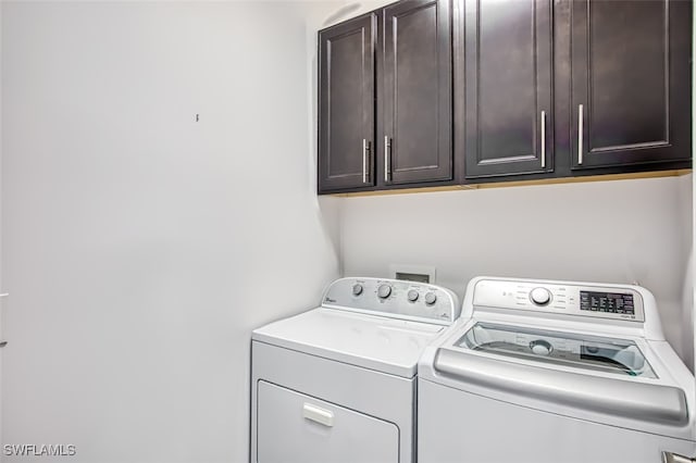 clothes washing area featuring cabinets and washing machine and dryer