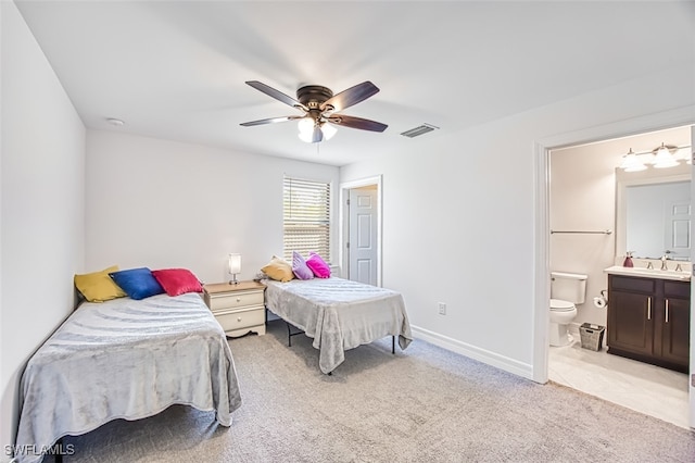 bedroom with light carpet, ensuite bath, and ceiling fan