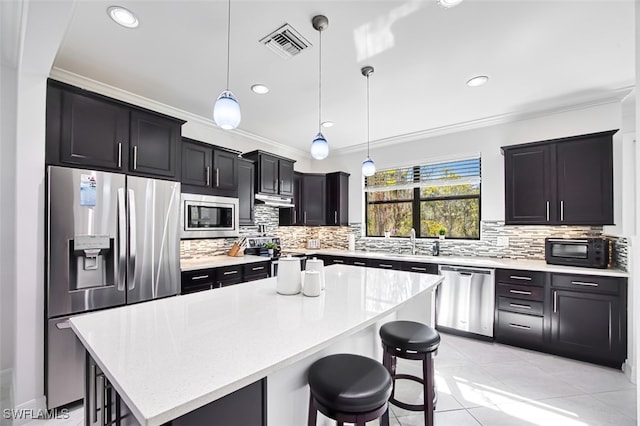 kitchen featuring a kitchen bar, a kitchen island, hanging light fixtures, and appliances with stainless steel finishes