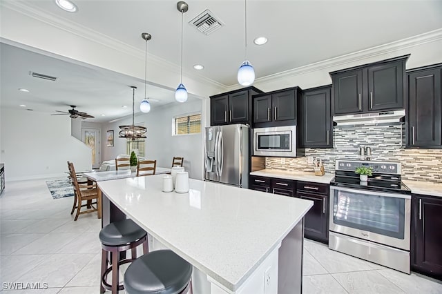 kitchen with appliances with stainless steel finishes, decorative light fixtures, a kitchen island, and ceiling fan