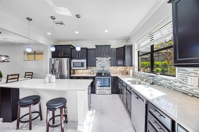 kitchen with a kitchen bar, ornamental molding, pendant lighting, and appliances with stainless steel finishes