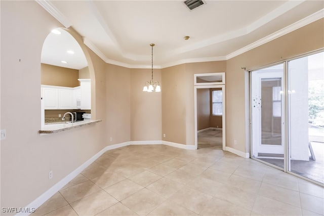 tiled spare room featuring a notable chandelier, crown molding, sink, and plenty of natural light