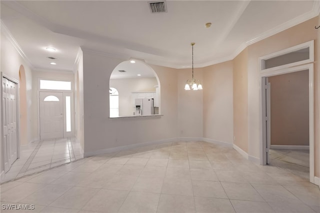 tiled spare room featuring ornamental molding and a chandelier