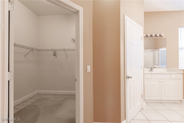 walk in closet featuring sink and light tile patterned floors