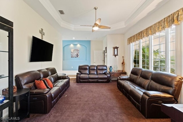 carpeted living room with ornamental molding, a raised ceiling, and ceiling fan