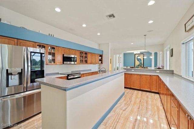 kitchen with a kitchen island, hanging light fixtures, kitchen peninsula, stainless steel appliances, and plenty of natural light