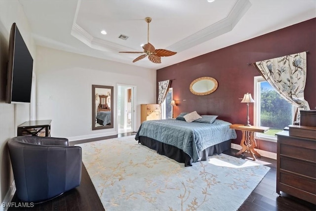 bedroom featuring dark wood-type flooring, ceiling fan, crown molding, and a raised ceiling