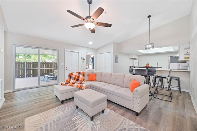 living room with light hardwood / wood-style flooring, ceiling fan, and lofted ceiling