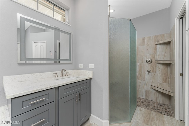 bathroom with wood-type flooring, vanity, and tiled shower