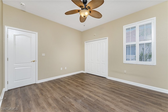 unfurnished bedroom with ceiling fan, a closet, and dark wood-type flooring