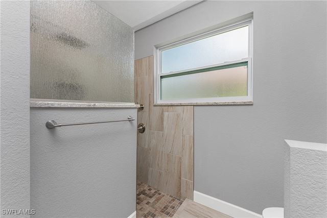 bathroom featuring a tile shower and toilet