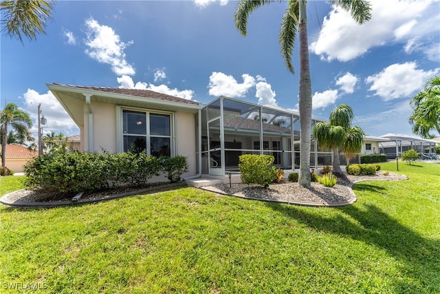 back of property with a lawn and glass enclosure