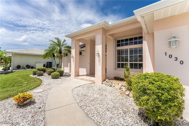 property entrance featuring a lawn and cooling unit