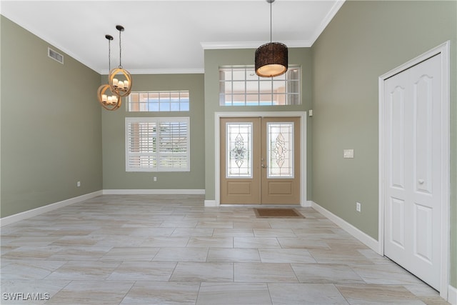 foyer entrance with french doors, a chandelier, and ornamental molding