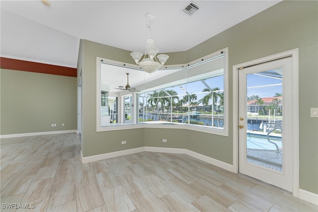 unfurnished dining area with ceiling fan with notable chandelier, light wood-type flooring, a water view, and a wealth of natural light