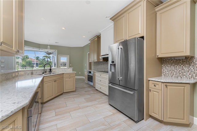 kitchen with sink, decorative light fixtures, stainless steel appliances, light stone countertops, and decorative backsplash