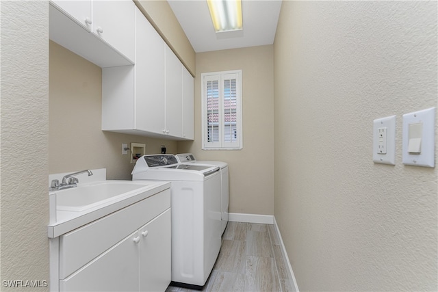 laundry room featuring light hardwood / wood-style floors, separate washer and dryer, sink, and cabinets