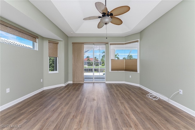 spare room with a tray ceiling, ceiling fan, and hardwood / wood-style floors