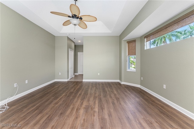 spare room featuring a tray ceiling, ceiling fan, and dark hardwood / wood-style flooring