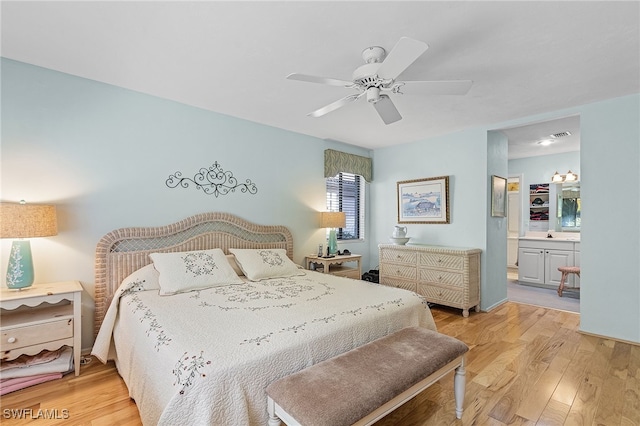 bedroom featuring light wood-type flooring, ensuite bath, and ceiling fan