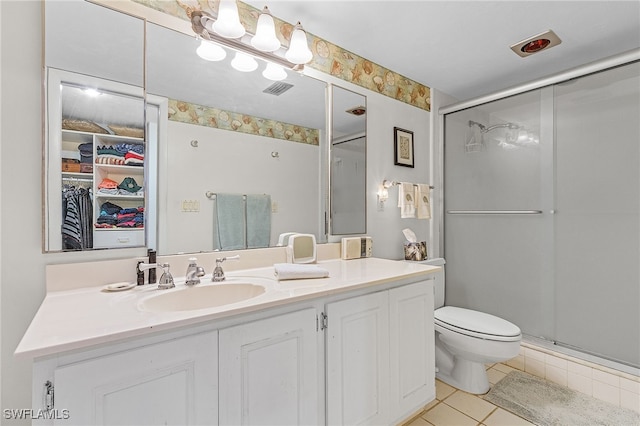 bathroom featuring vanity, toilet, tile patterned flooring, and a shower with door