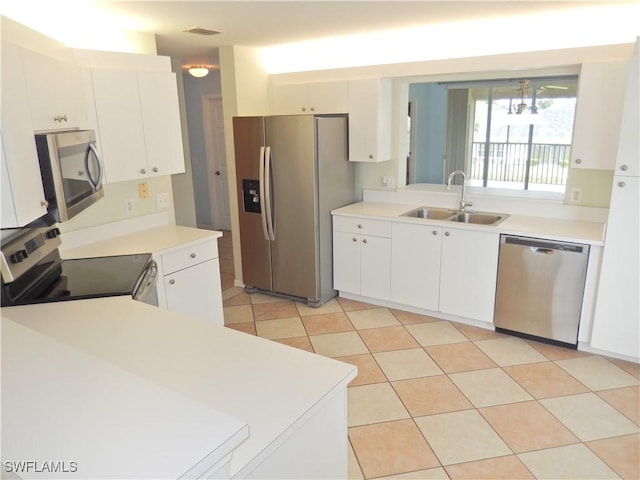 kitchen with light tile patterned flooring, appliances with stainless steel finishes, white cabinetry, and sink