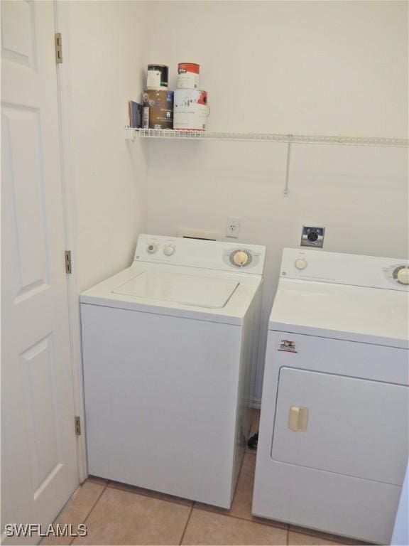 laundry room with washer and clothes dryer and light tile patterned floors